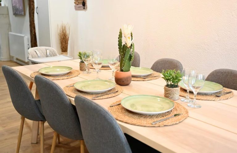 Table dressée avec assiettes vertes, verres et plantes en pot, ambiance chaleureuse.