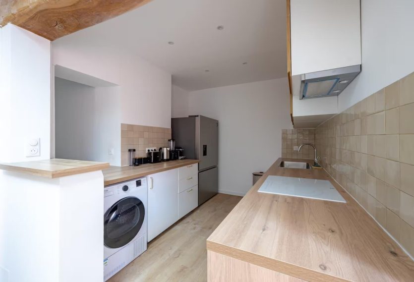 Cuisine moderne avec un plan de travail en bois et des appareils électroménagers.