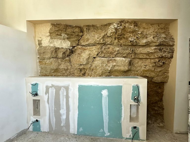 Mur en pierre apparente avec une surface lisse et des trous pour des installations.