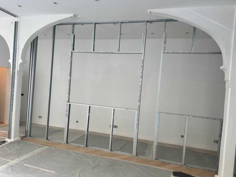 Structure en métal en cours de montage dans un espace vide avec des arches décoratives.