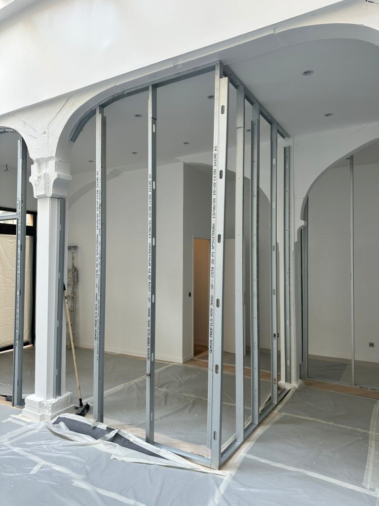 Construction intérieure avec des montants métalliques et un sol recouvert.