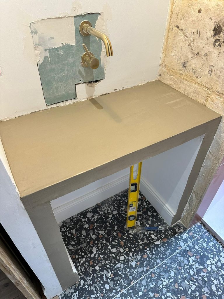 Surface en béton avec robinet, niveau à bulle et murs en cours de rénovation.