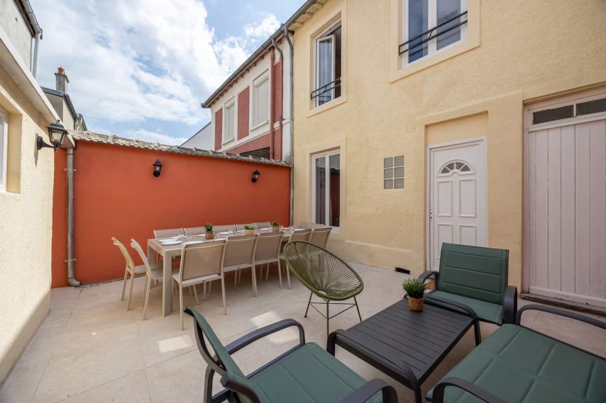 Terrasse ensoleillée avec mobilier de jardin et mur coloré.