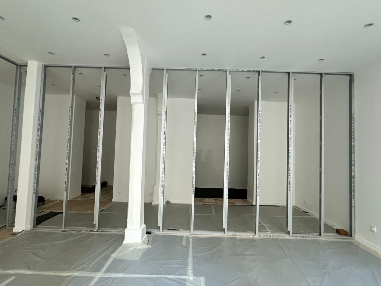 Intérieur d'une pièce avec des cloisons en métal et des murs blancs.